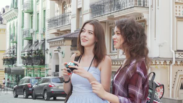 Two Lovely Female Friends Taking Photos of the City While Travelling Together