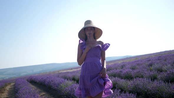 Woman in a Short Purple Dress and a Hat Stands on a Lavender Field alt