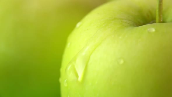 Super Closeup of a Drop of Water Flowing Down a Large Ripe Juicy Green Apple alt