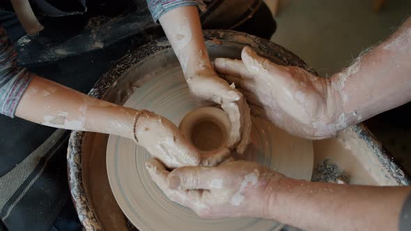 Top View of Boy and Man's Hands Shaping Clay Into Pot Working in Pottery Studio alt