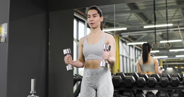 Portrait of Sporty Young Woman Lifting Dumbbells in Gym