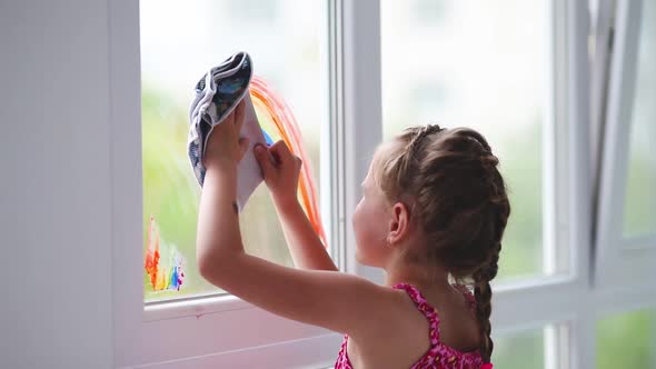 A girl washes a painted rainbow from a window. No quarantine. The end of self-isolation