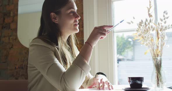 Two caucasian businesswomen sitting at table with coffee, talking, having business meeting alt