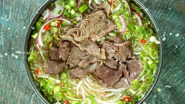 Super Slow Motion Detail Shot of Sliced Beef Falling Into Pho Soup at 1000 Fps. alt
