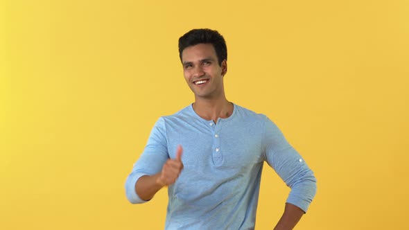 Young smiling Indian man pointing and giving thumbs up empowering you