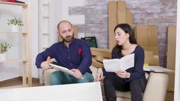 Couple Assembling Furniture Using Instructions in Their New Apartment alt