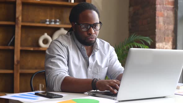Young African American Male Employee Using a Laptop alt