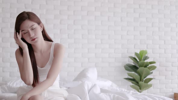 Asian women wake up happy and smile on white bed in bedroom.