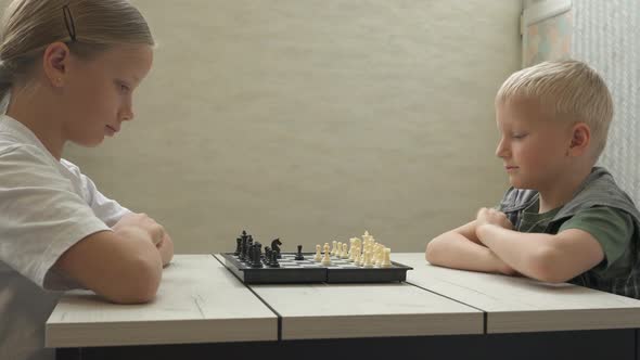 Brother and Sister Playing Chess at Home