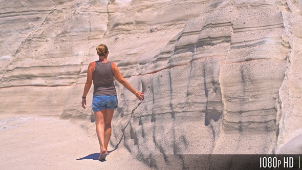 Woman hand touching eroded rock formation at Sarakiniko beach, Milos, Greece alt