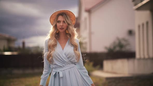 Portrait of Beautiful Woman with Long Blonde Hair in Long Blue Dress Walks Outside and Smiles