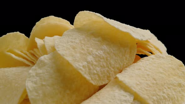 Macro shot of potato chips rotation on black background, close up.