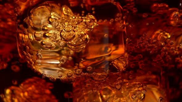Ice Cubes with Bubbles in a Rotating Glass of Cola. Abstract Super Close-up Shot, UHD alt