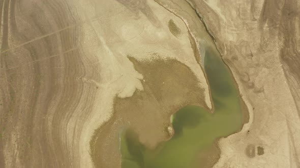 A dry lake bed showing little remaining water and lines where water has disappeared, during a drough alt