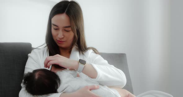 Mother is Breastfeeding Her Newborn Baby in the Nursery