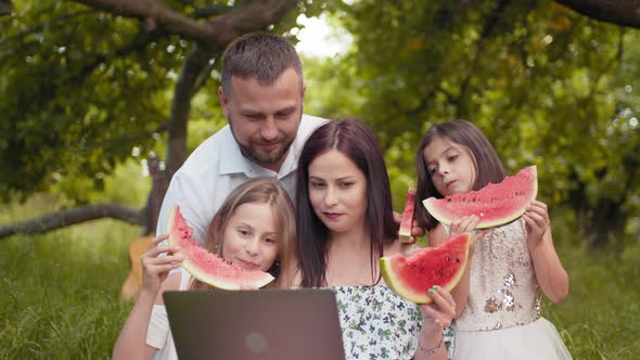 Young Parents with Two Little Daughters Having Video Call on Laptop During alt