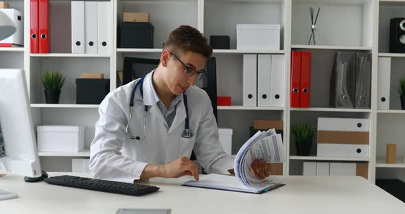 Young Doctor Looking at Documents at Workplace