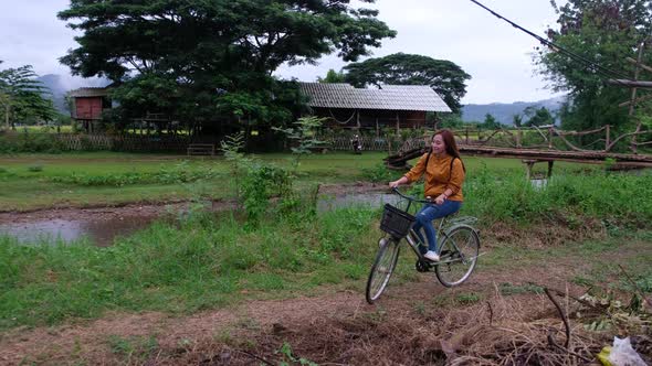 A female tourist riding bicycle in rural village in Thailand