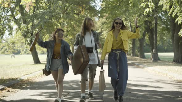 Wide Shot Carefree 1960s Hippies Walking Along Sunny Summer Road Talking alt