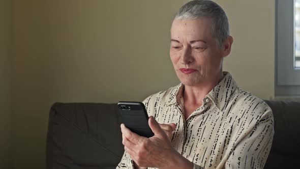 An Elderly Woman with Very Short Hair After Chemotherapy is Talking on a Cell Phone