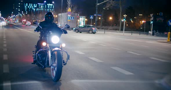 Rock Biker Rides Motorcycle on City Roads and Streets at Late Night in Warsaw