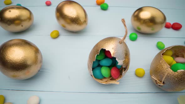 Golden Decorative Easter Eggs Filled with Colorful Candies on Wooden Table Close Up