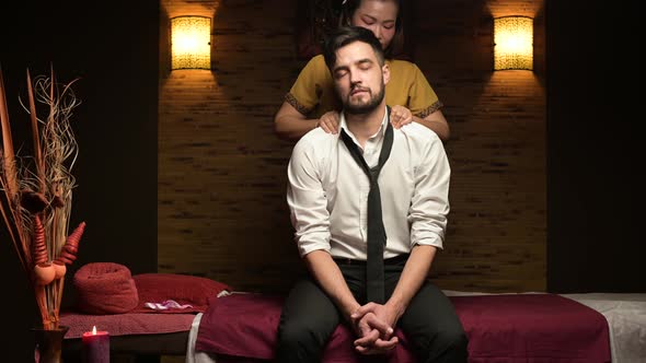 Tired manager in a Thai massage parlor. The masseur kneads the back of a man alt