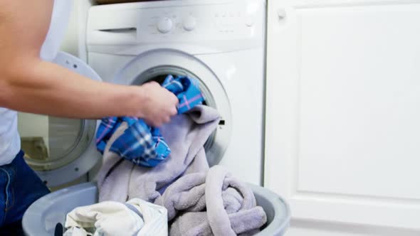 Man putting dirty clothes into washing machine alt
