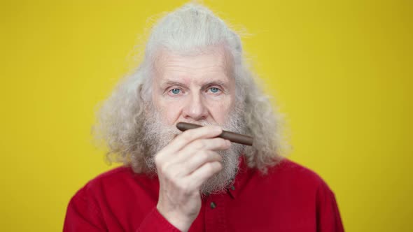 Headshot of Stylish Senior Man Smelling Cigar Looking at Camera alt
