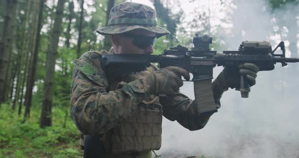 Modern Soldier with Rifle in Dens Forest with Smoke in Background