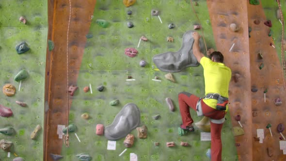 Climber Moves on the Mountain in a Room with a Rope on the Insurance and a Bag for Chalk Overcoming alt