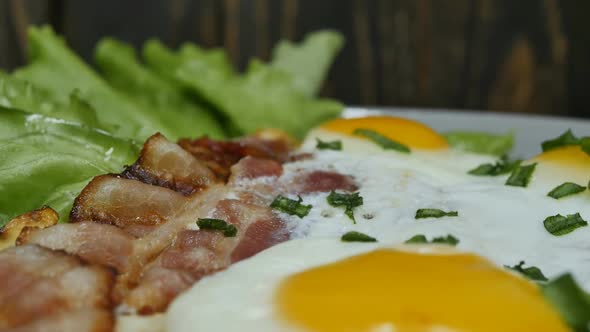 Juicy Fried Bacon with Eggs in a Plate with Green Salad Leaves