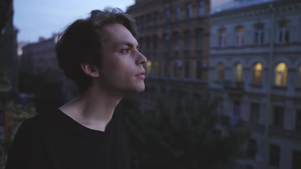 A Young Man with Makeup Standing on the Balcony Smoking a Cigarette