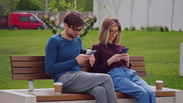 Couple friends using smartphones outdoor park. Coffee Break. alt