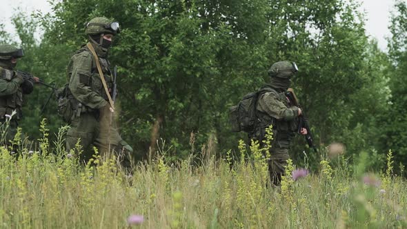 Soldiers in Camouflage with Assault Rifle Walking Through the Field Military Action in the Steppe alt