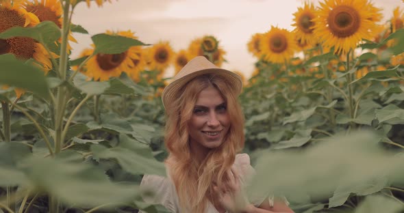 Beautiful Girl is Standing in a Sunflower Field and Smiling Looking at the Camera
