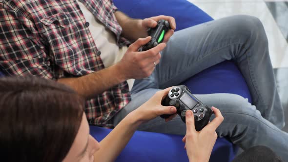 Hands of a Man and a Woman Enjoying Playing Video Games with a Console Gamepad in Their Hands