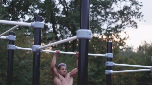 dolly shot of a young ripped man doing muscle ups in an outdoor calisthenics sports park alt