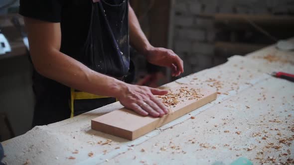 Carpentry Works in Workshop Man Worker Brings the Wooden Board to the Table and Shakes Off the alt