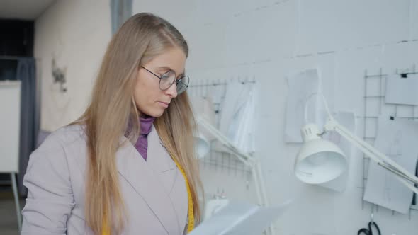 Slow Motion of Clothes Designer Hanging Sketches on Board Working in Modern Studio alt