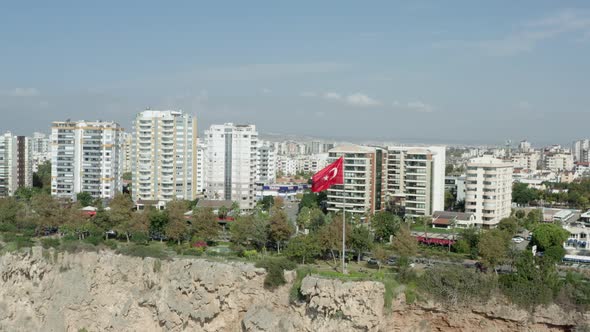 Drone Video Flag of Turkey Evolving on a Rock in a City alt