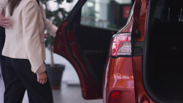 Closeup Red Car Rear Lights with Unrecognizable Caucasian Man Opening Door and Woman Sitting on alt