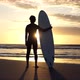Surfer looking out at ocean as sun rises in the distance - VideoHive Item for Sale