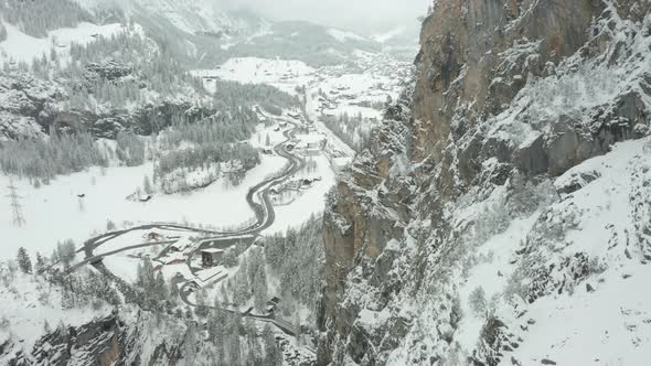 Aerial of snow covered mountain ridge with a small Swiss town in the background alt