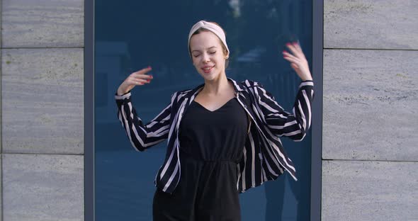 Young Active Cheerful Student Girl Wears Headband and Striped Jacket Actively Moves Her Arms Posing alt