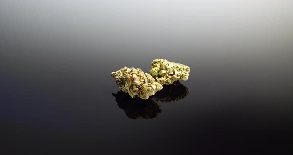 Two marijuana flower buds ready to be smoked isolated on a black background. alt