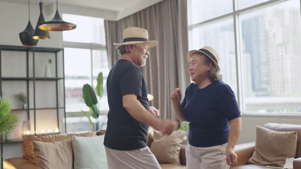Asian senior people dance along together laugh smile cheerful in living room