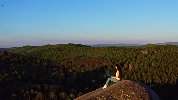Aerial Shot of a Freelance Woman Working on a Laptop Sitting on a Mountaintop
