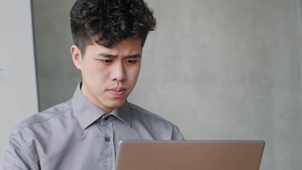 Portrait of Pensive Asian Business Man Working with Laptop Solves Application Problems Error in alt