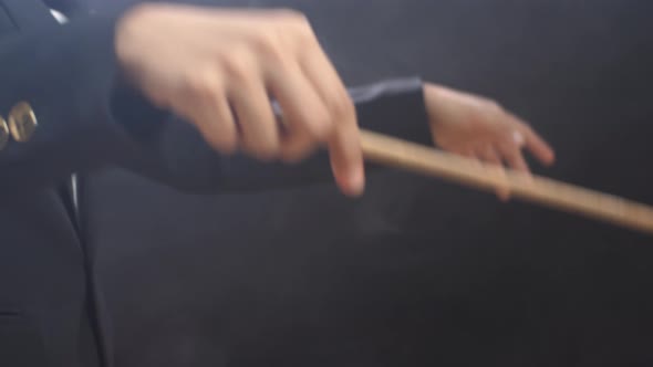 Close Up Of Side View Conductor's Hands Holding A Baton And Moving In The Black Studio alt